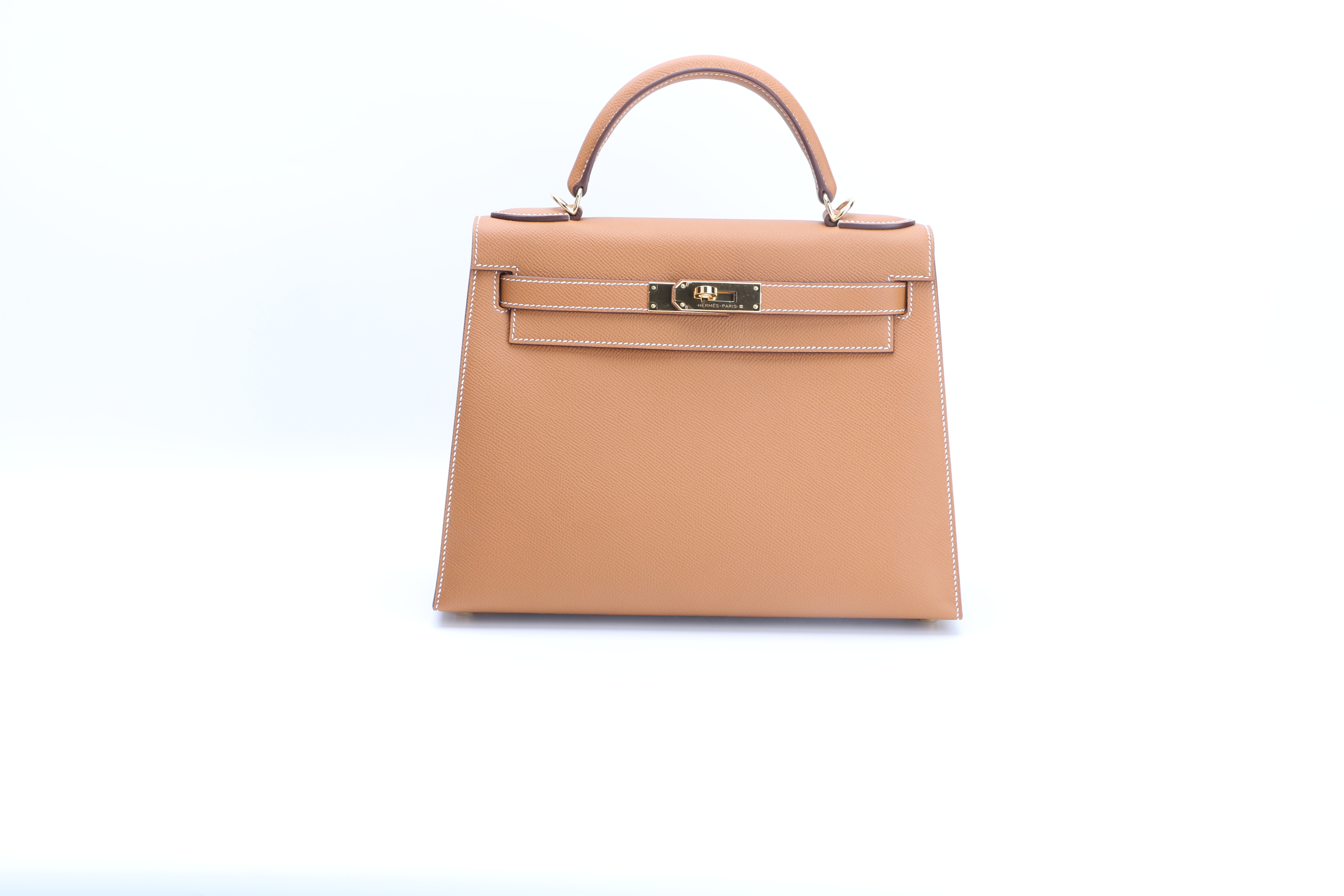Front view of a replica Hermes Kelly Sellier showing its trapezoidal outline and balanced closure Front view of a replica Hermes Kelly Sellier showing its trapezoidal outline and balanced closure