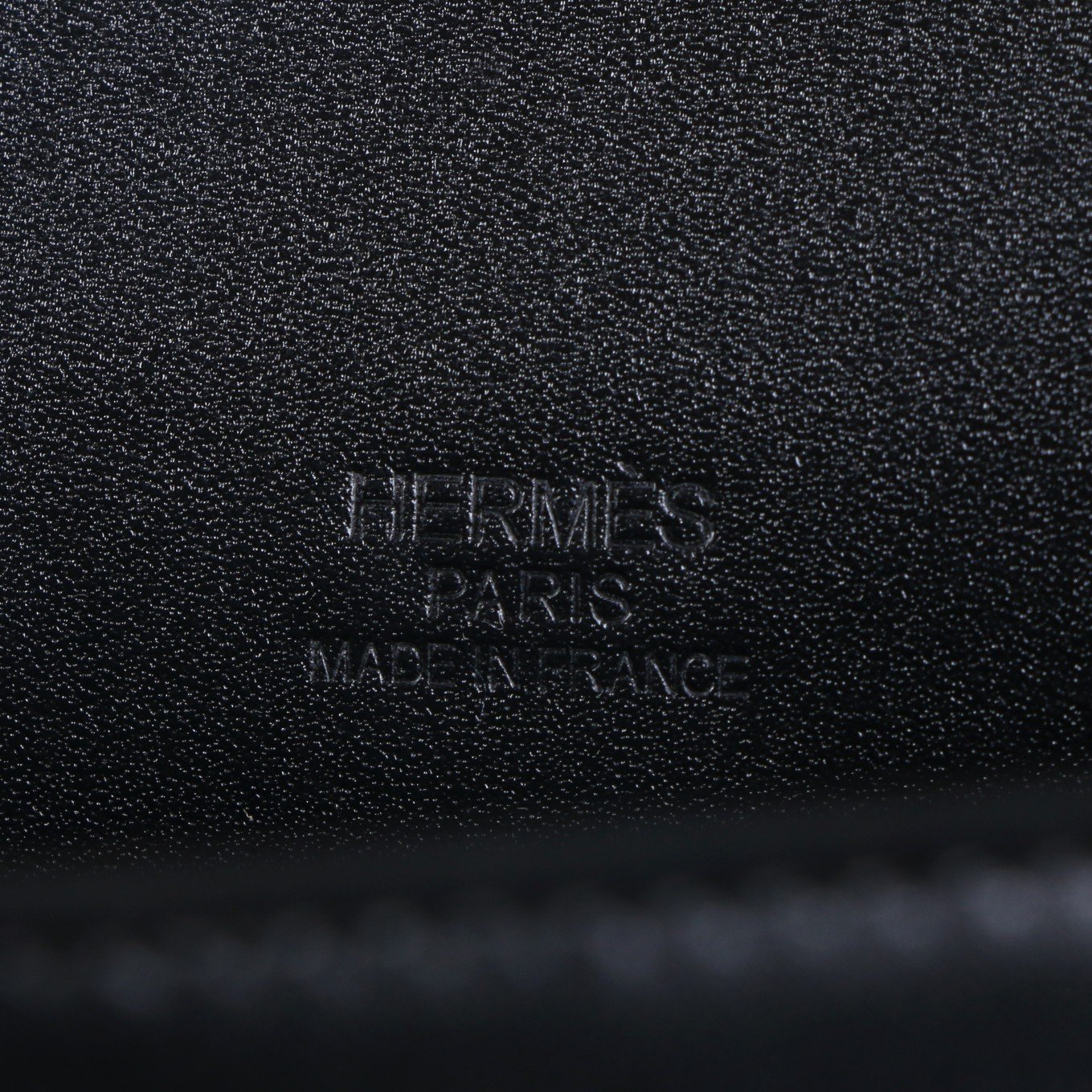 Close-up of an Hermès Paris stamp on black pebbled material
